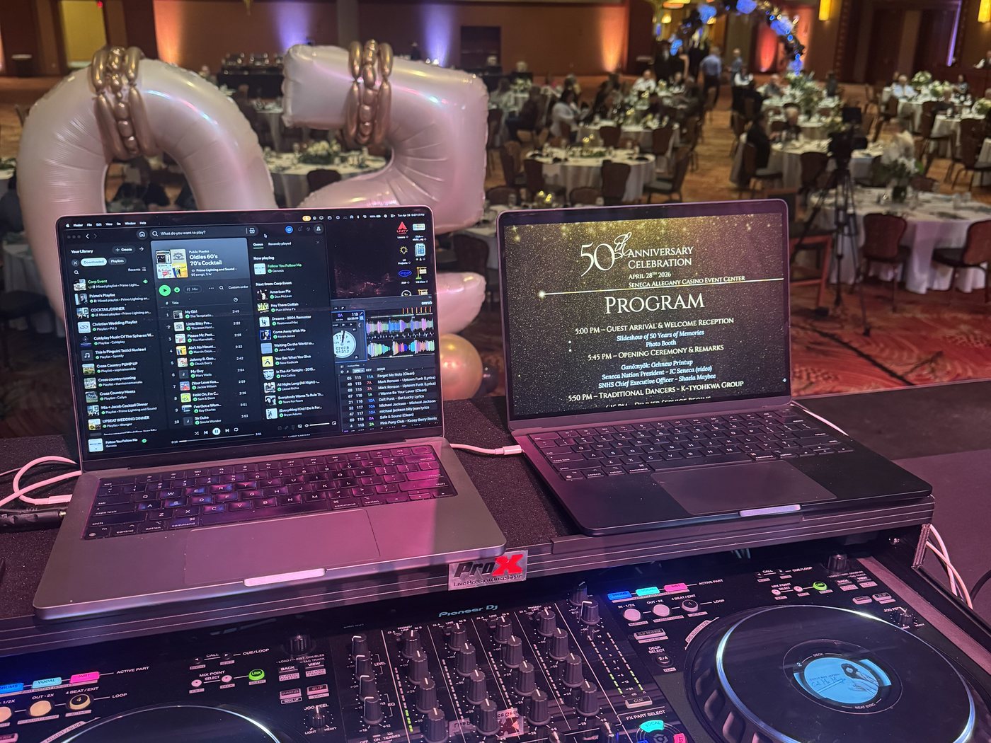 The night's run-of-show open on a laptop beside the decks at a 50th anniversary celebration