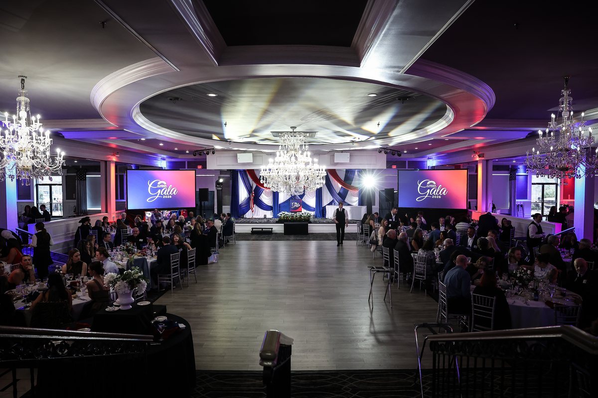 Corporate gala ballroom with dual screens, stage production and custom uplighting
