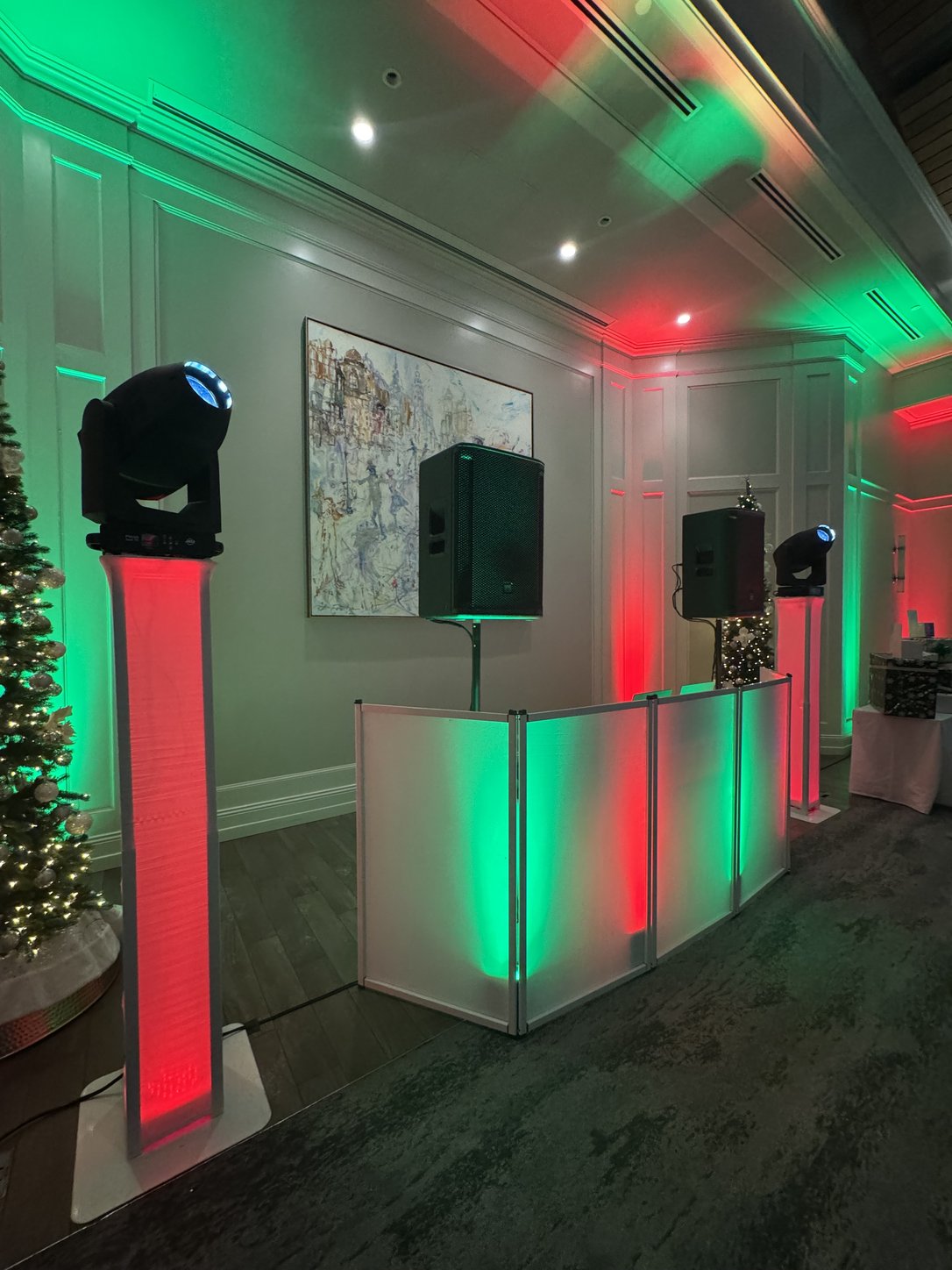 A Primo DJ booth and moving lights set for a holiday party, the room lit in red and green