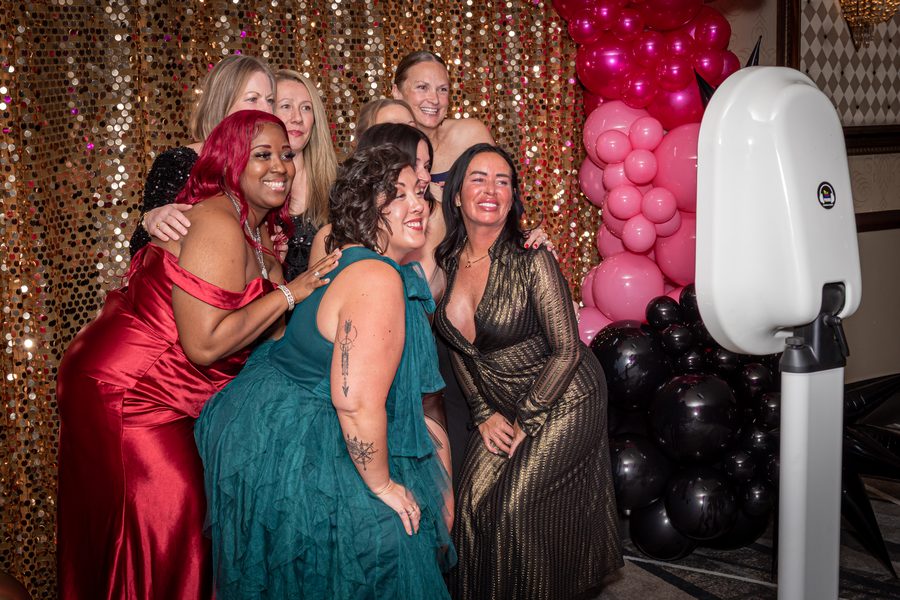Guests posing together at a Primo photo booth with a sequin backdrop