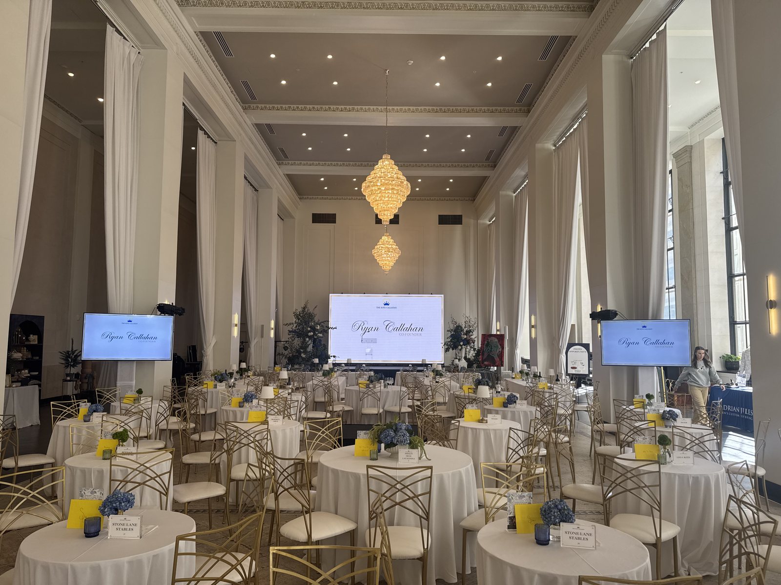 A ballroom fully set and ready before guests arrive — screens, drape, chandeliers and every table dressed
